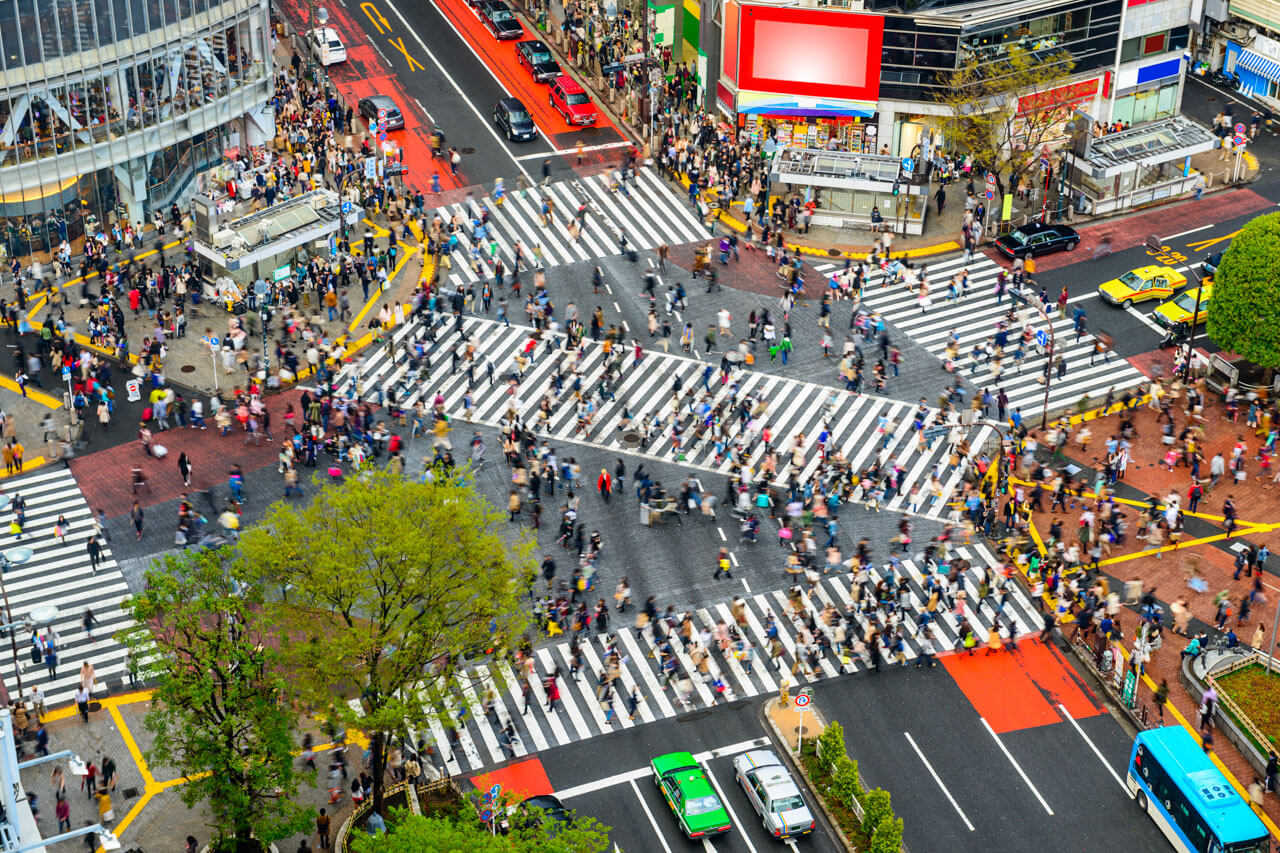 Luftaufnahme der Shibuya Kreuzung mit vielen Menschen auf breiten Zebrastreifen