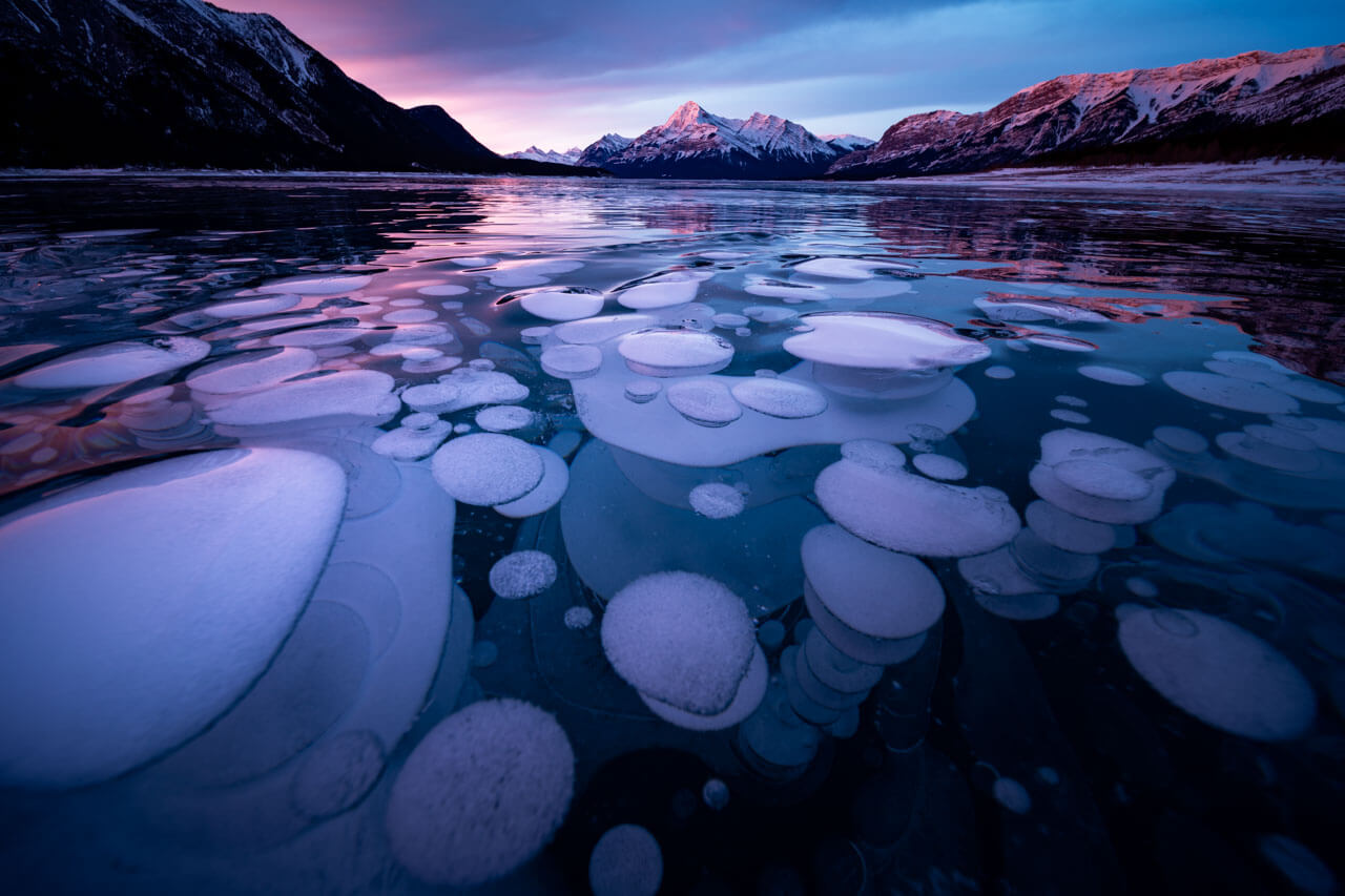 Eisblasen im Abraham Lake bei Sonnenaufgang zeigen die winterliche Schönheit Kanadas auf Sprachreise
