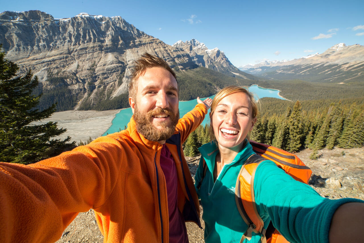 Lachendes Wanderpaar mit Rucksäcken am Aussichtspunkt, Erinnerung an eine Sprachreise