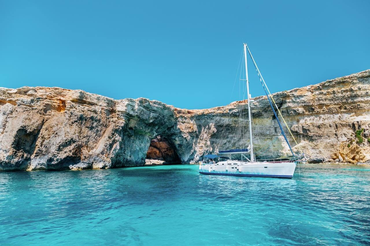 Segelboot vor heller Felsküste mit Meeresgrotte Konversation üben bei der Bootstour