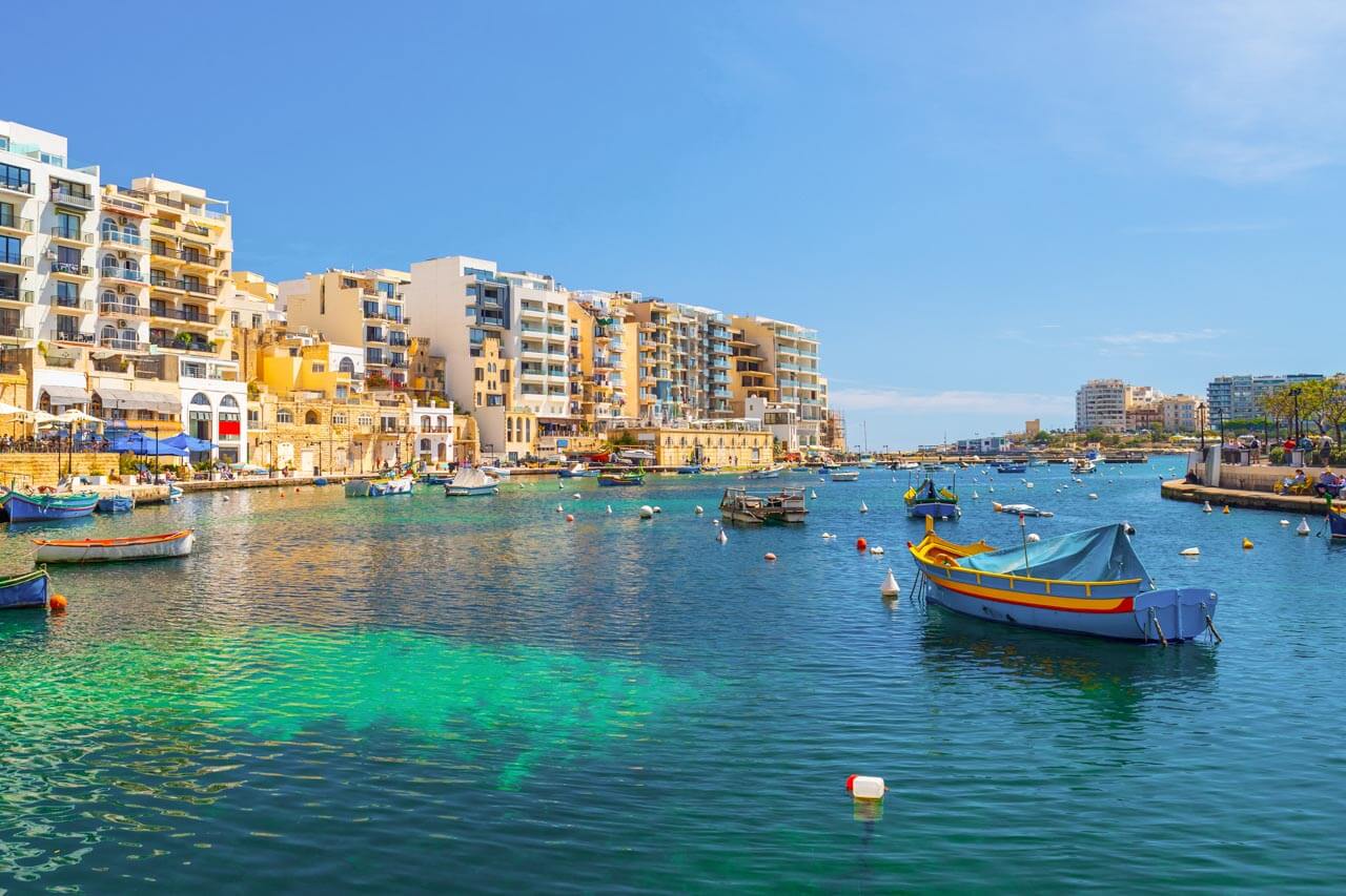 Spinola Bay mit bunten Fischerbooten und Ufercafés im Sonnenschein. Konversation im Café und Redewendungen anwenden