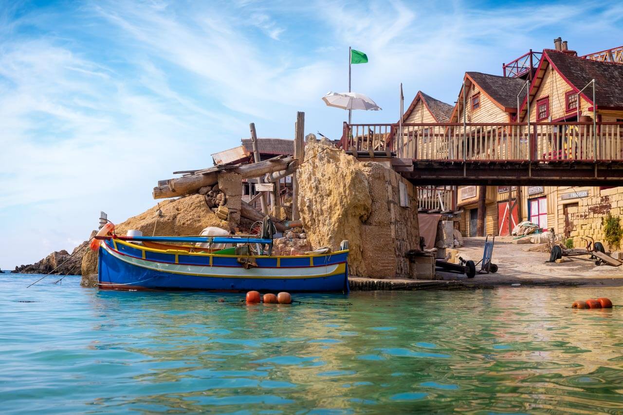 Traditionelles Fischerboot bei farbenfrohen Häusern als Symbol für Sprachkurs Englisch am Meer