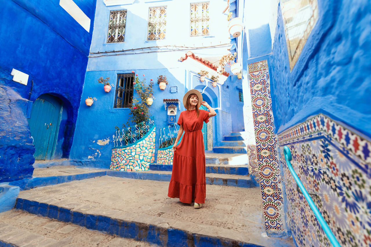 Frau in rotem Kleid in blauen Gassen, Sprachreise Marokko mit Kultur erleben.