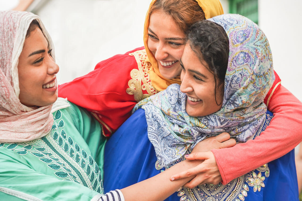 Drei Freundinnen in traditionellen Gewändern, Hörverstehen und Smalltalk üben.