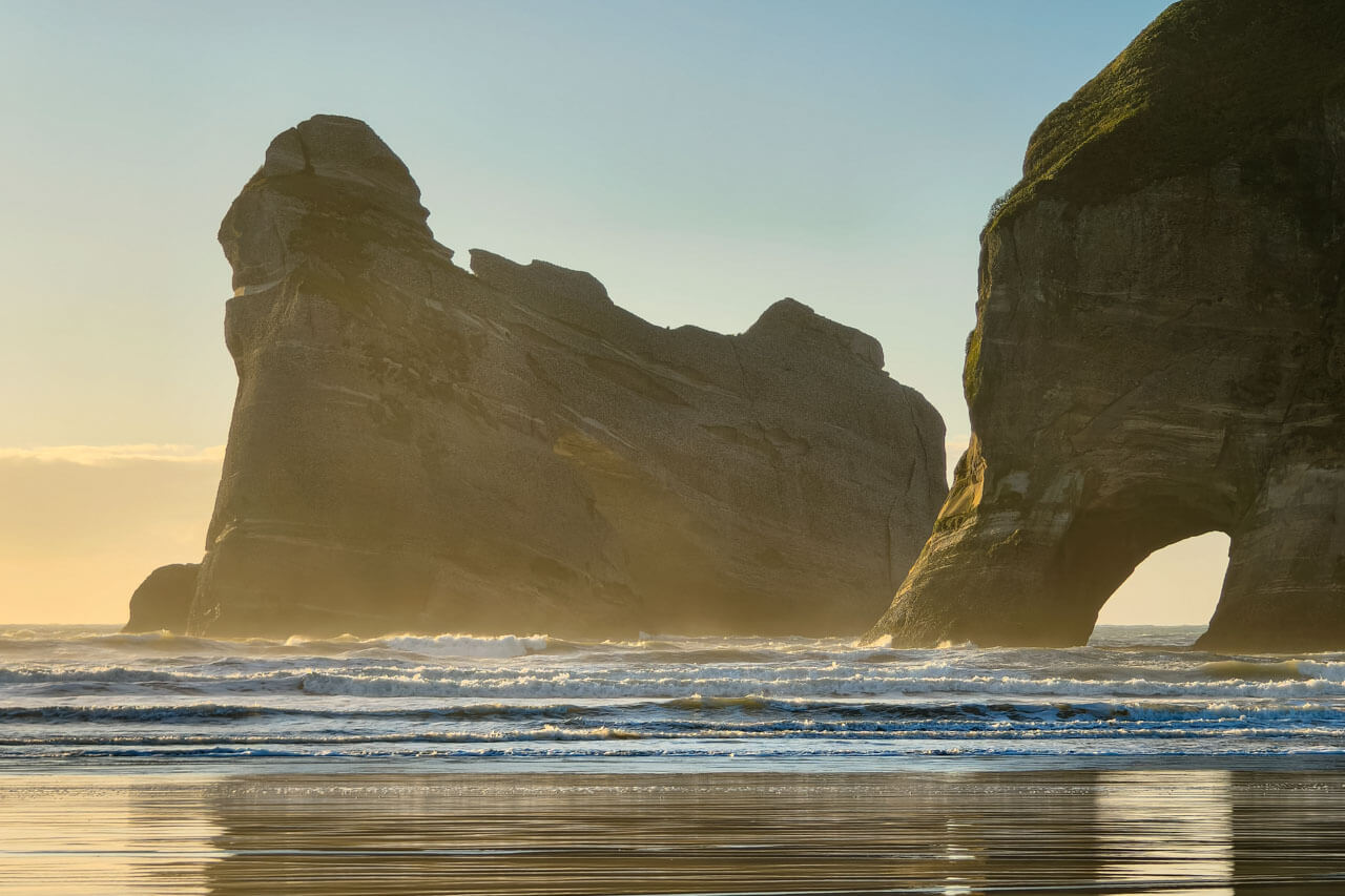 Felsbogen am Strand bei Abendlicht, Konversation üben beim Spaziergang am Meer.