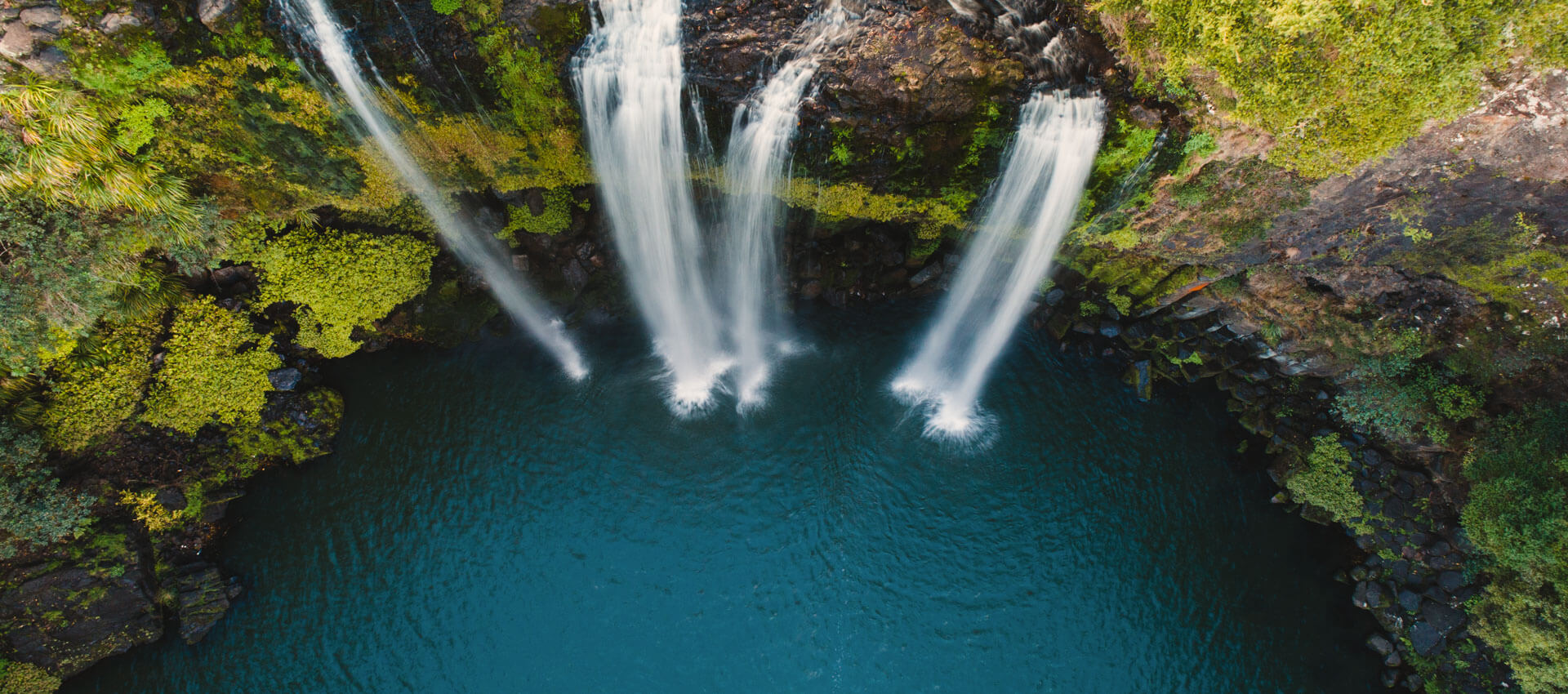 Drei Wasserfälle stürzen in türkisfarbenes Becken, Hörverstehen üben in Naturkulisse.
