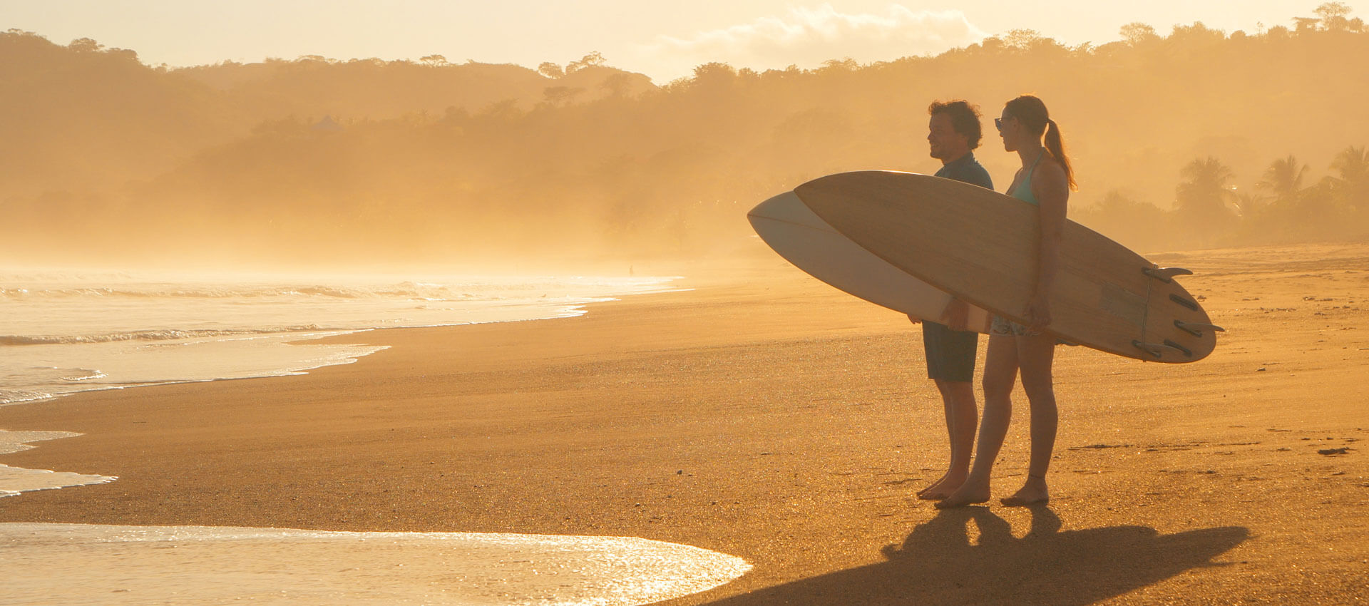Surferpaar am Strand bei Sonnenuntergang Freizeit nach Sprachreise Aussprache verbessern