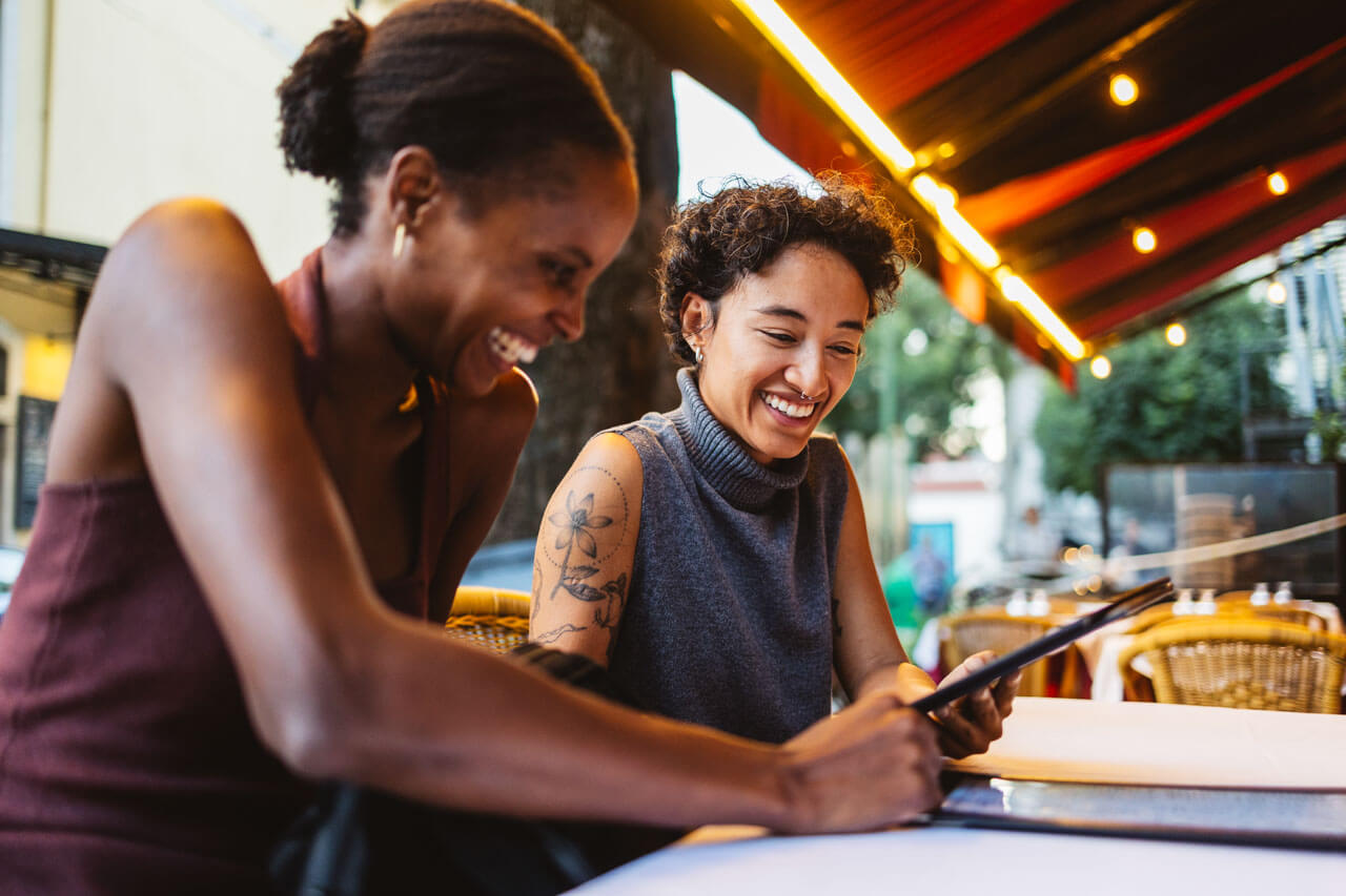 Zwei Freundinnen lachen beim Restaurantbesuch in Lissabon – Sprachkurs Portugal
