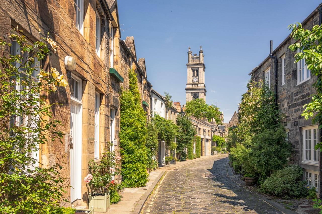 Blumenreiche Kopfsteinpflastergasse mit Turm, gemütlicher Spaziergang zum Sprachkurs in der Altstadt.