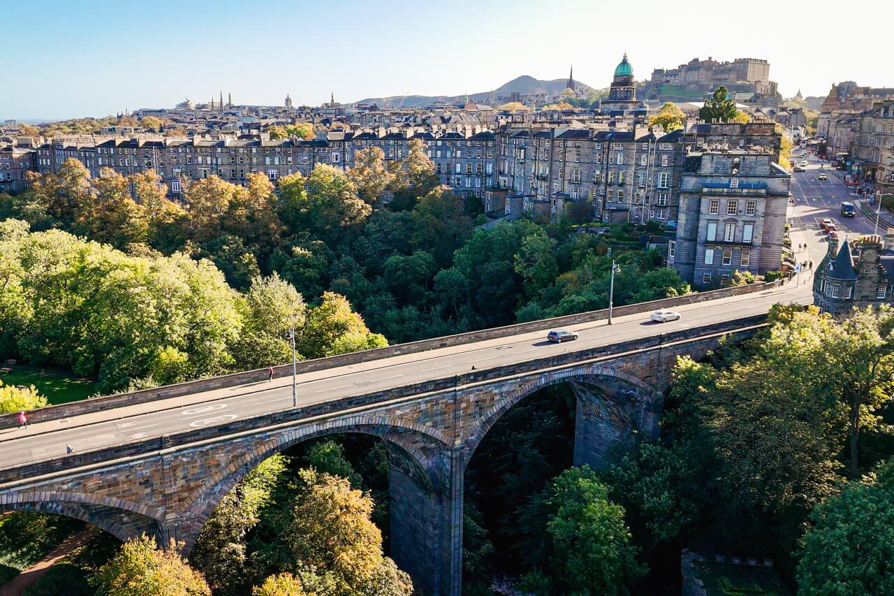 Bogenbrücke über grünem Tal mit Stadtpanorama, Konversation üben auf einem geführten Stadtspaziergang.