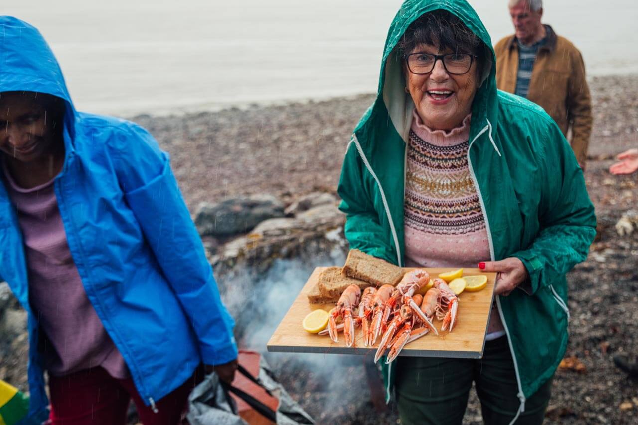 Strandpicknick im Nieselregen, Platte mit Meeresfrüchten. Konversation üben beim gemeinsamen Essen.