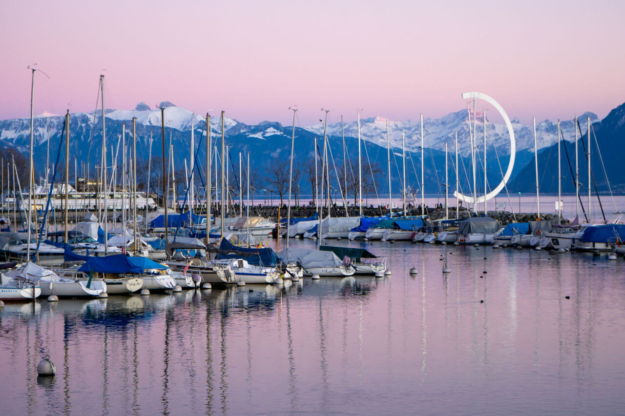 Boote im Hafen vor Alpen im Abendlicht, Hörverstehen trainieren beim Spaziergang
