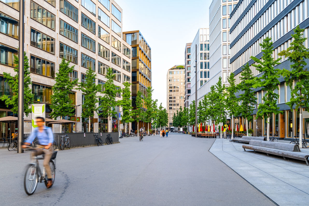 Moderner Boulevard mit Radfahrern, Business-Deutsch im Sprachkurs, Grammatik üben in urbaner Umgebung.