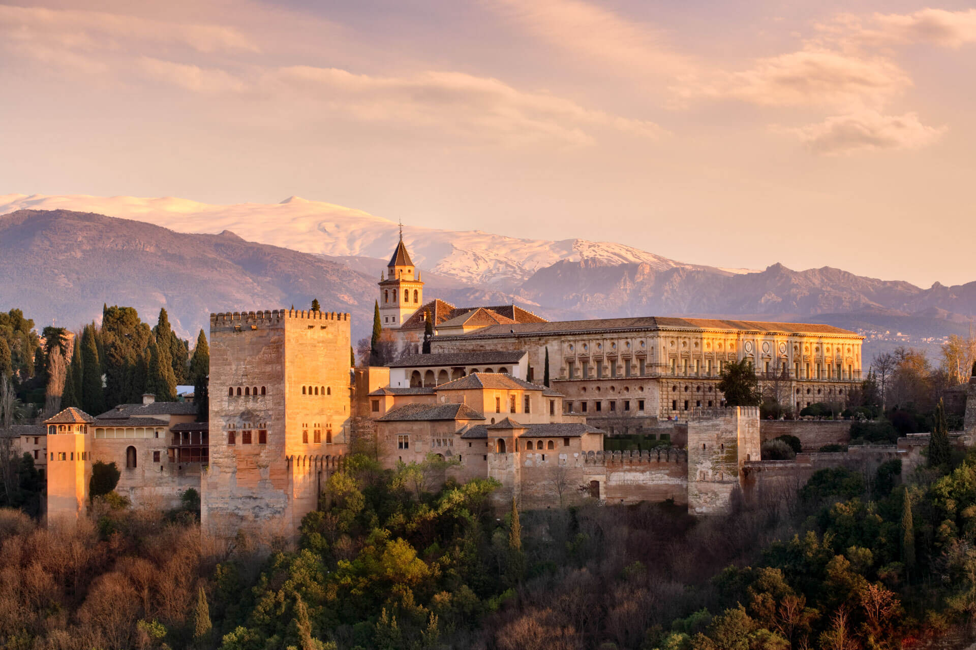 Alhambra bei Sonnenuntergang mit schneebedeckter Sierra Nevada im Hintergrund.