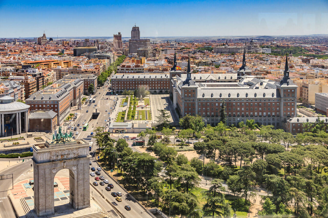 Panorama vom Faro de Moncloa über den Arco de la Victoria, die Ciudad Universitaria und baumgesäumte Avenidas.