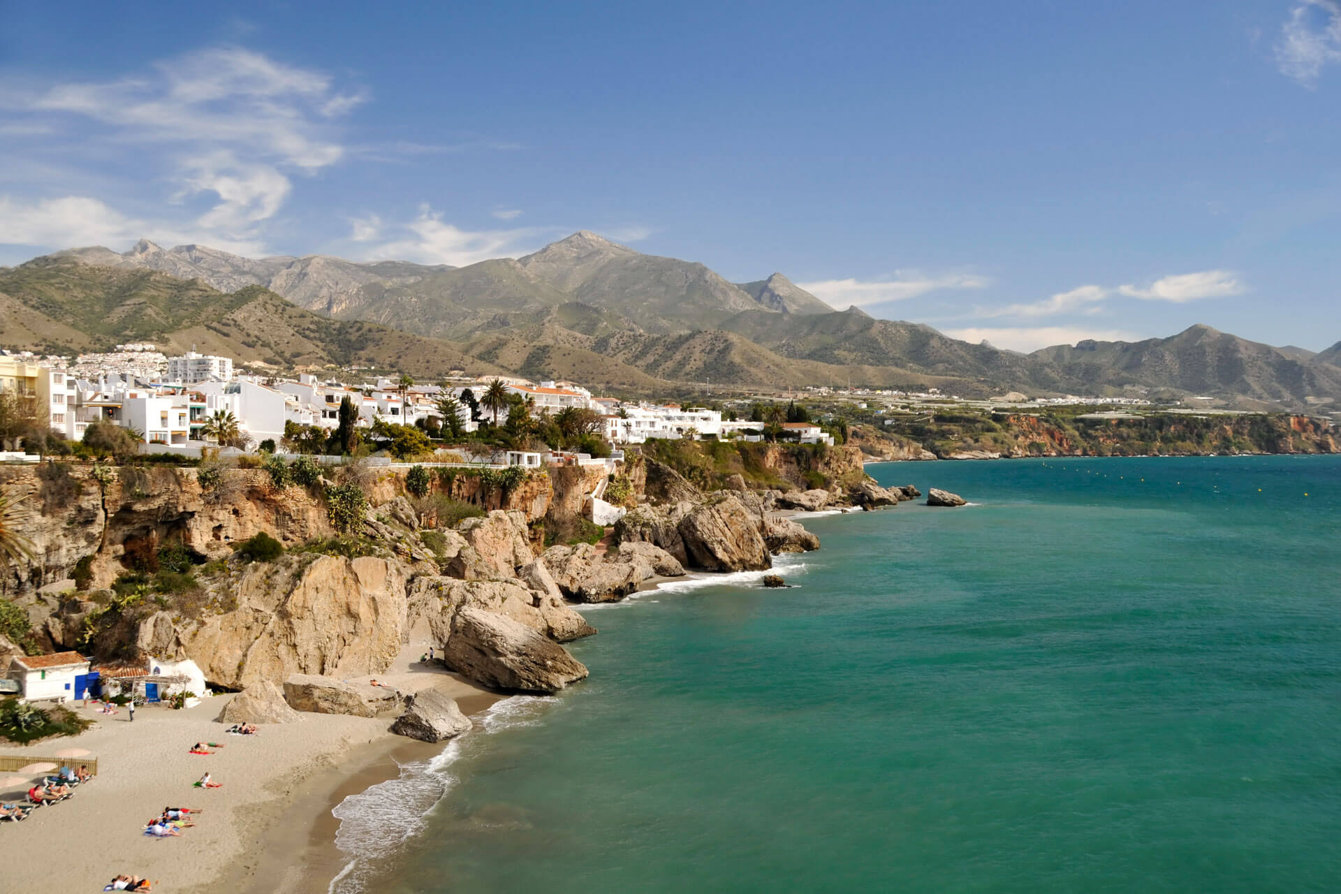 Nerja-Küste mit weißen Häusern auf Klippen, türkisblauem Meer und Bergkulisse der Sierra de Almijara