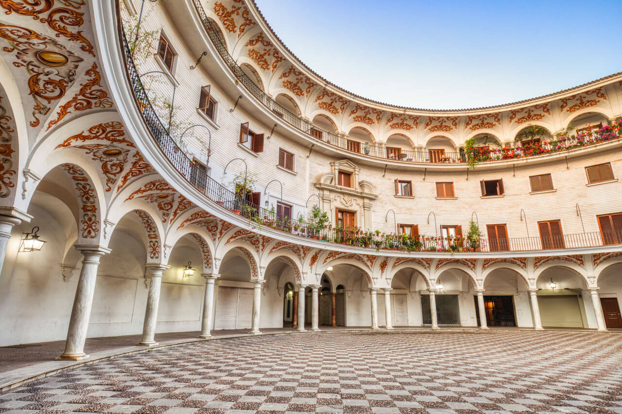 Runder Innenhof der Plaza del Cabildo in Sevilla mit Arkaden und verzierten Stuckbögen.