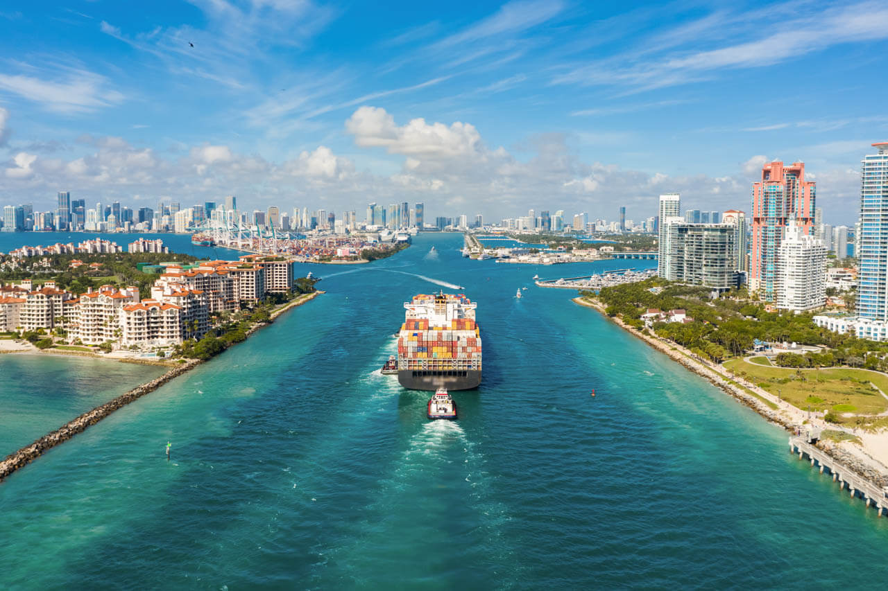 Blick auf Containerfrachter im Hafen, Skyline im Hintergrund. Business Englisch im Sprachkurs.