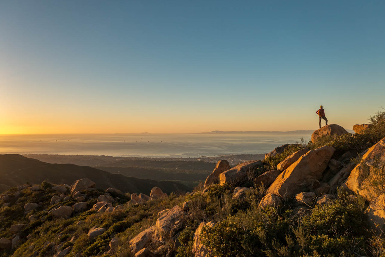 Wanderer auf Felsen über der Küste im Abendlicht, Aussprache verbessern.