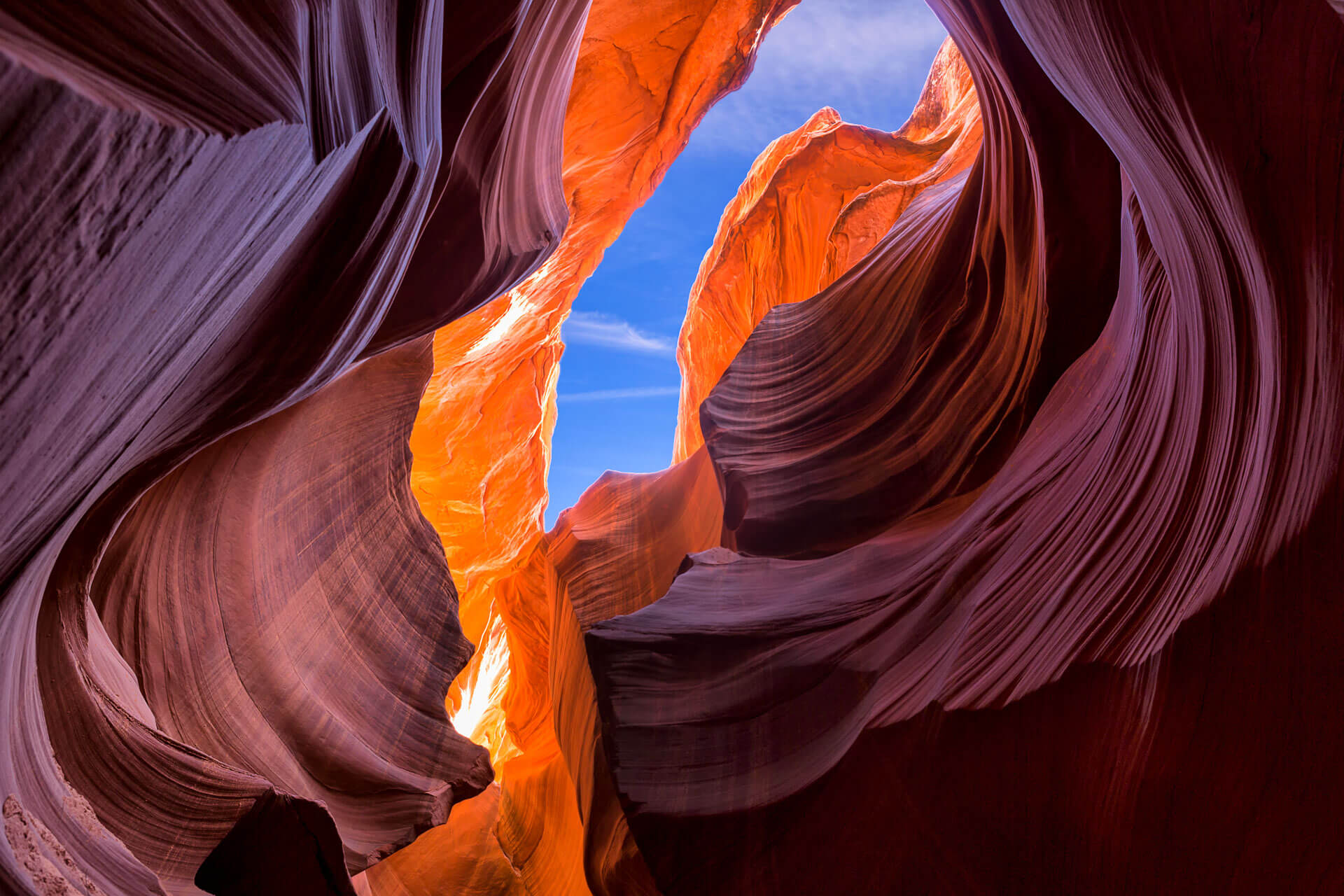Blick durch die geschwungenen Felswände des Antelope Canyon auf den blauen Himmel.