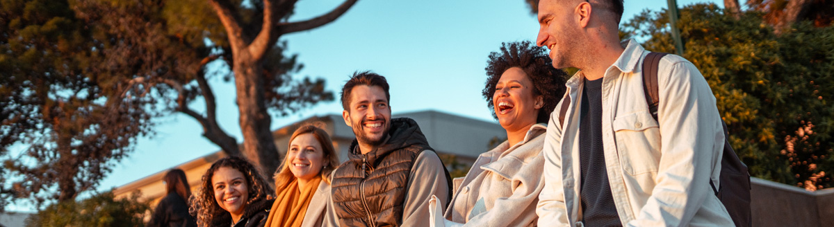 Gruppe Erwachsener lacht gemeinsam im Sonnenuntergang während einer Sprachreise.
