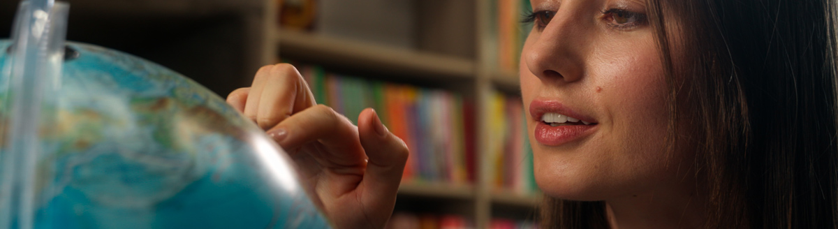 Frau betrachtet interessiert einen Globus und plant ihre Bildungsurlaub Sprachreise ins Ausland.