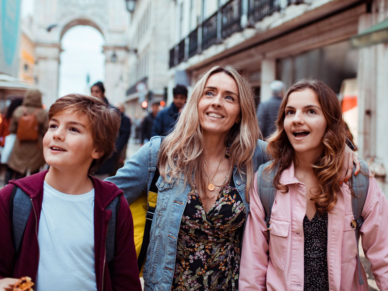 Mutter mit zwei Kindern erkundet fröhlich eine Altstadt während einer Sprachreise.